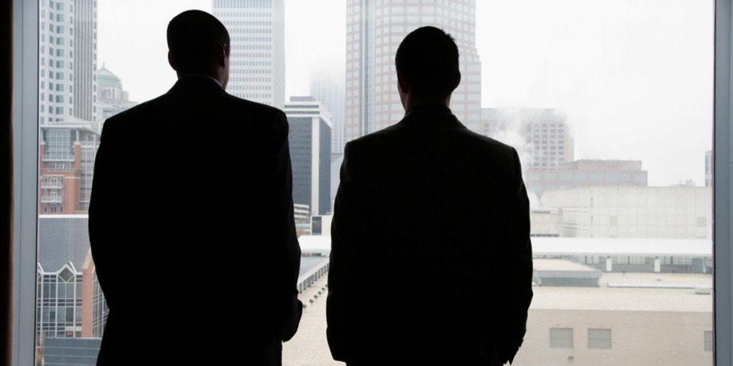 A mentoring relationship depicted by two men staring out of a window with their backs to the camera