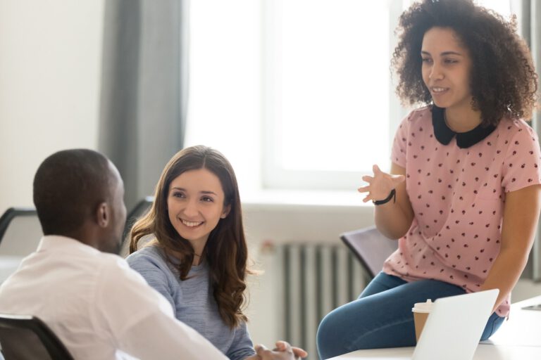 Friendly young african american woman mentoring male and female colleagues