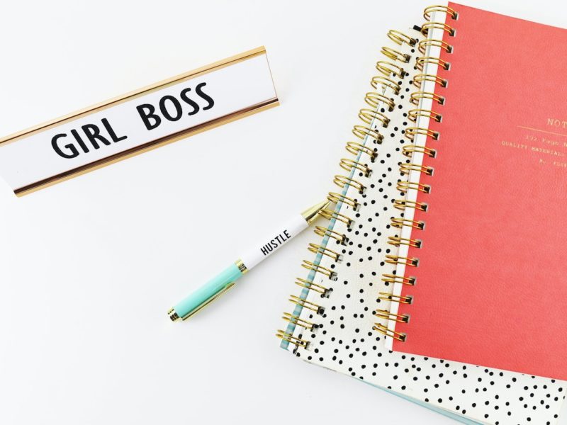 Girl boss name plate on work desk with books limiting yourself by focusing on job title