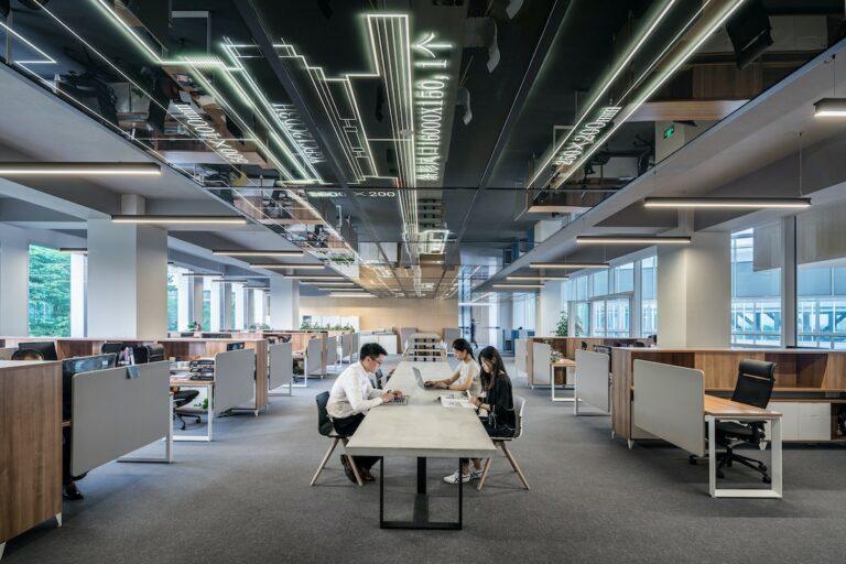 Almost empty office with 3 people sat at a desk in the centre - 7 Career Management and Mentoring Challenges to Overcome in 2023