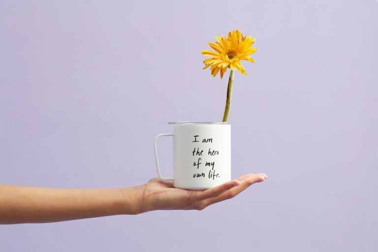 Career Success. Putting Your Strengths to Work. A Self-Assessment Guide. Mug in a hand with message I am the hero of my own life with sunflower in the mug