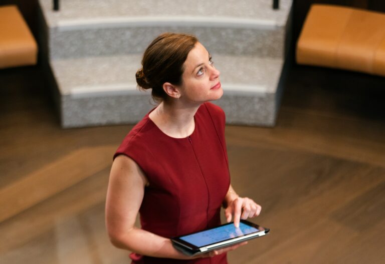 Setting Yourself Up for Success - woman looking upwards with and ipad in her hands wearing a red dress