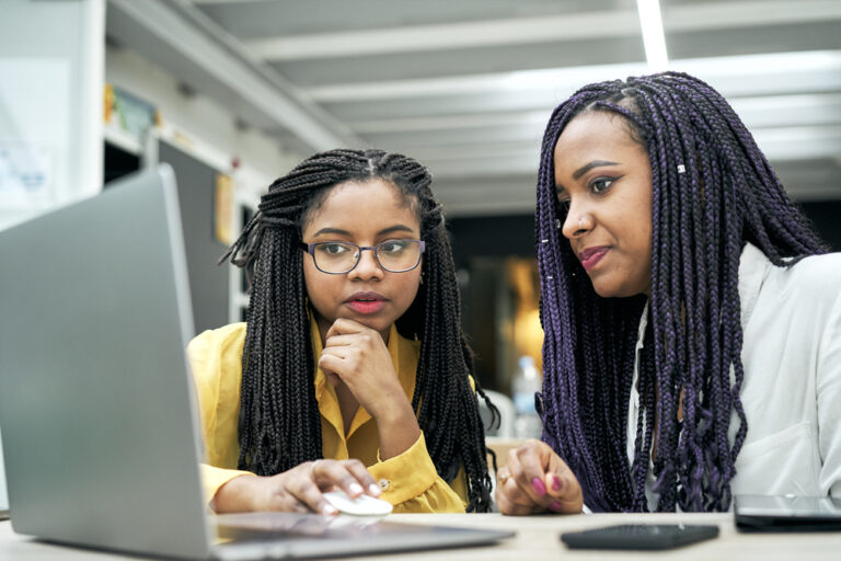 International mentoring day two black women with braided hair sat at a computer