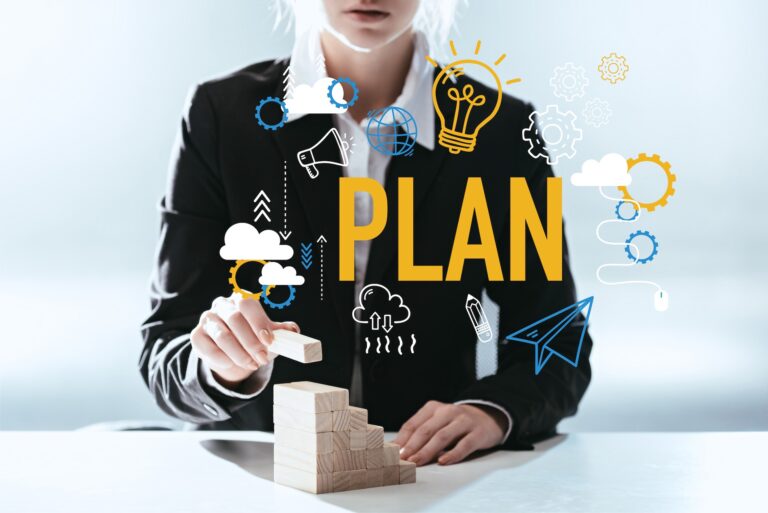 A woman in a suit putting toy building blocks on top of each other, with the word 'plan' written boldly across the image. Illustrating the steps and preparation needed to have a great career conversation