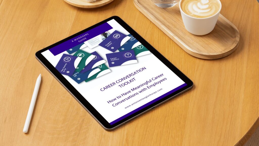 Tablet on a wooden table displaying the Career Conversation Toolkit by Antoinette Oglethorpe, a manager’s guide on how to have meaningful career conversations with employees, alongside a stylus and a cup of coffee.