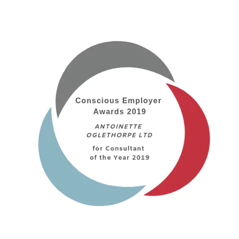 A circular logo with three curved segments in grey, red, and blue surrounds the text: “Conscious Employer Awards 2019, Antoinette Oglethorpe Ltd for Consultant of the Year 2019”.