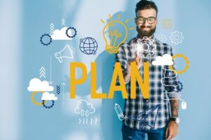A smiling man in glasses and a checked shirt stands against a blue background, touching virtual icons related to planning and Employee Ownership. The word 
