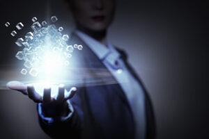 A person in a suit holds out their hand, with glowing floating cubes and digital light effects emanating above their palm—symbolising futuristic promotions in a dark, high-tech setting.