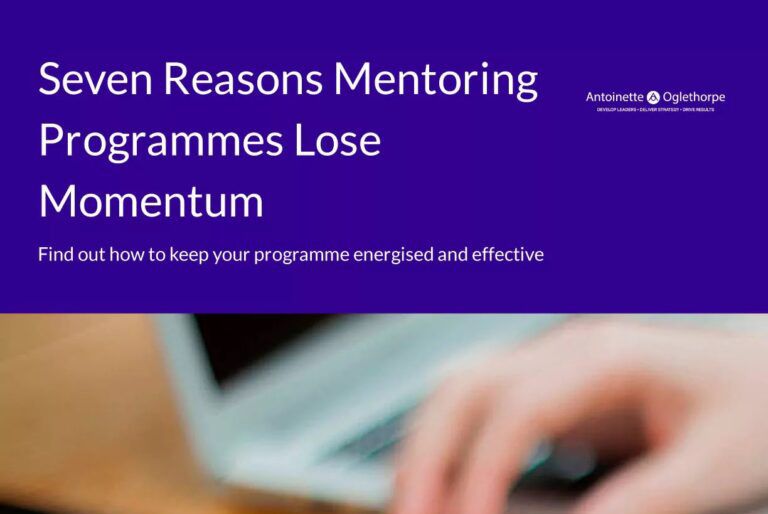 A blurred hand types on a laptop keyboard beneath a purple PDF cover that reads, "Seven Reasons Mentoring Programmes Lose Momentum" with a brief description and a company logo in the corner.